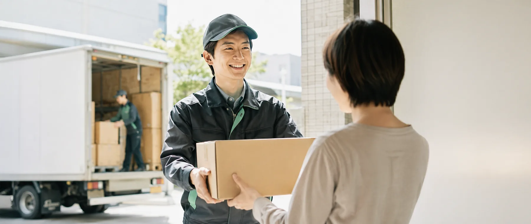 荷物を手渡す配達スタッフと笑顔で受け取るお客様
